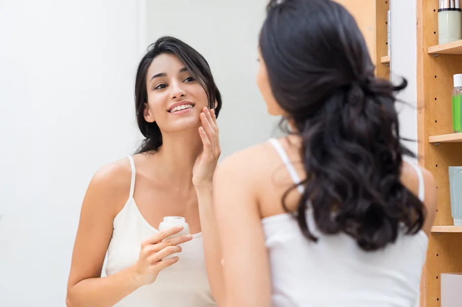 a woman applies facial moisturizer on her face